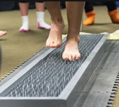 person with bare feet walking on a bed of nails
